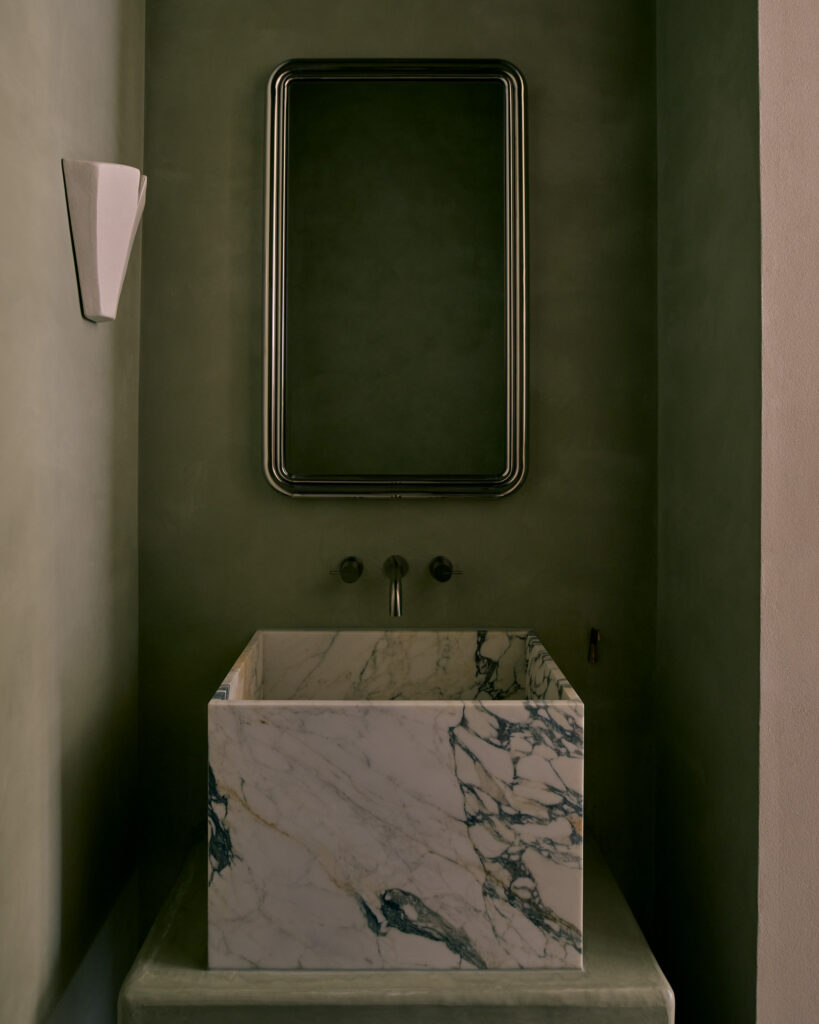 მუქი მწვანე სააბაზანოს დიზაინი, მარმარილოს ნიჟარა და კედლის სანათი.