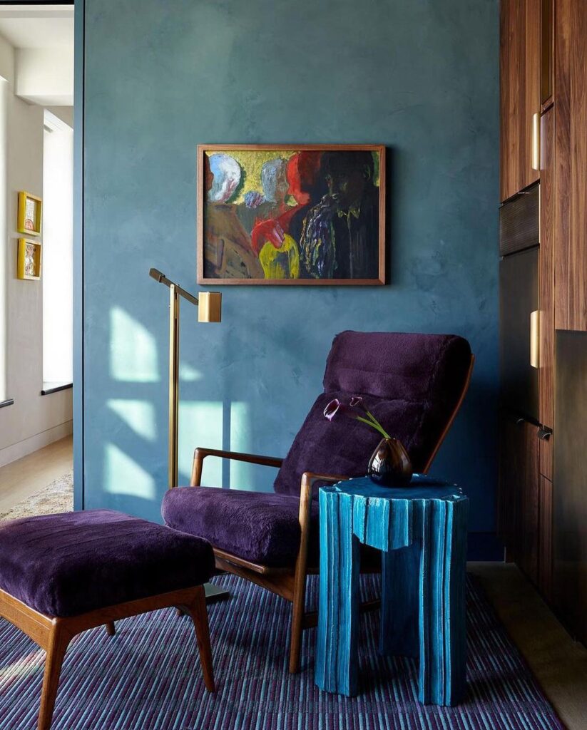 იასამნისფერი სავარძელი ლურჯი კედლის ფონზე და ფერადი ნახატი